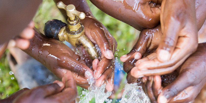 ugandan children washing their hands at an outdoor water tap